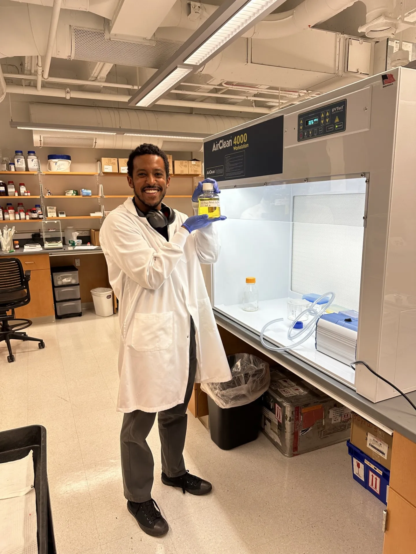 Ben in the laboratory holding a bottle with a yellow solution. 